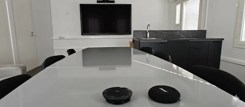 Moderni ja valoisa palaveritila Nummelassa, jossa on suuri näyttö ja keittiöpiste.